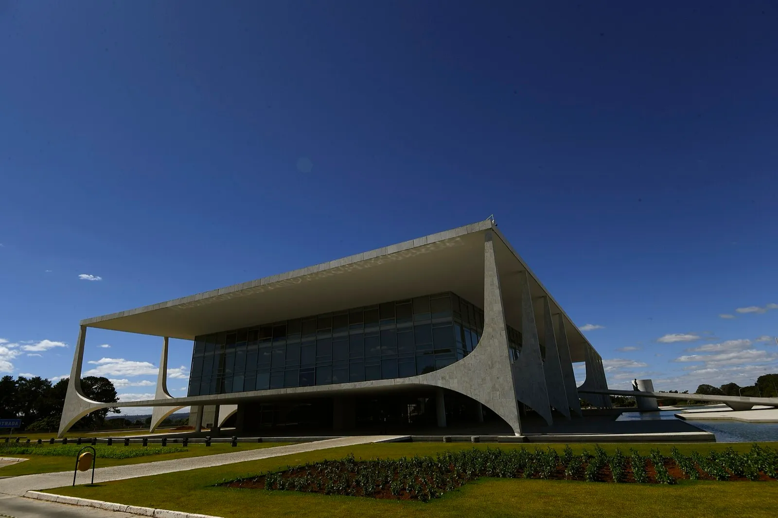 Fachada do Palácio do Planalto, com colunas curvas de concreto branco, sob céu azul.