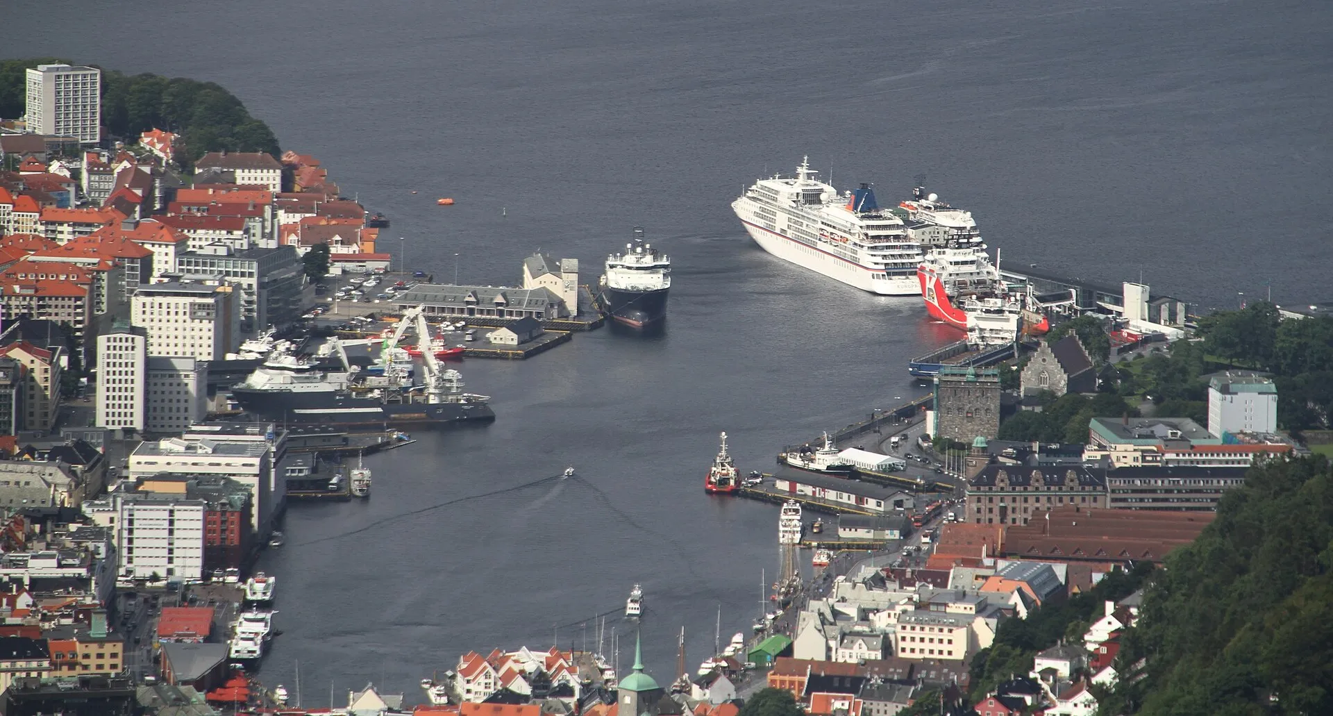 Vista aérea da baía de Vågen, em Bergen, com navios, cais e prédios ao redor da água.