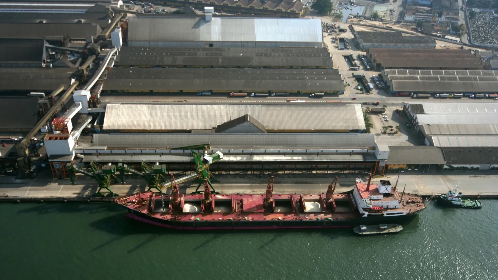 Vista aérea de navio atracado no terminal de exportação de grãos do Porto de Santos, ao lado de armazéns.