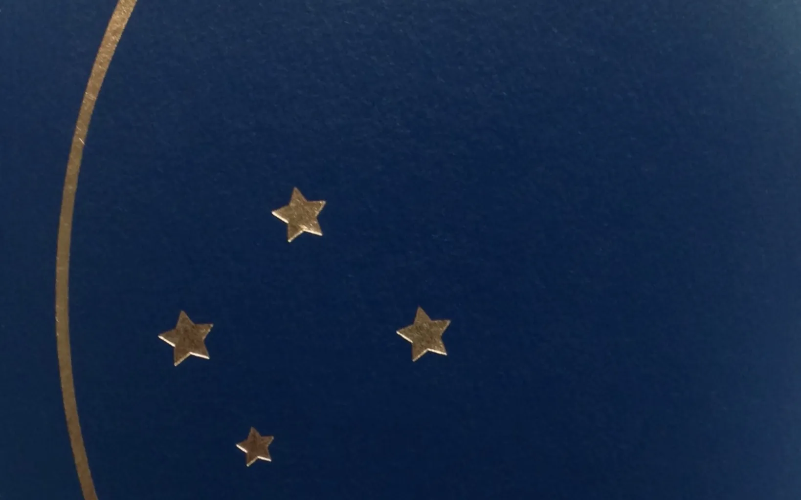 Detalhe ampliado da capa azul de um passaporte brasileiro, com estrelas douradas do brasão nacional.